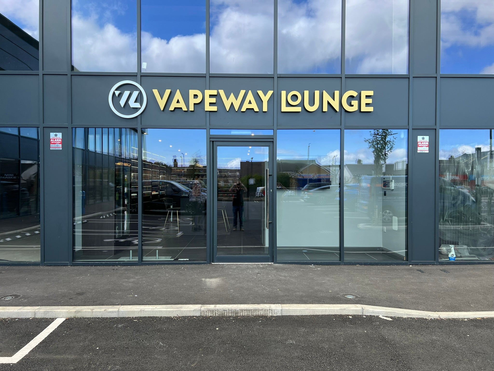 Completed VapeWay Lounge shopfront with illuminated gold acrylic lettering and a raised circular logo.