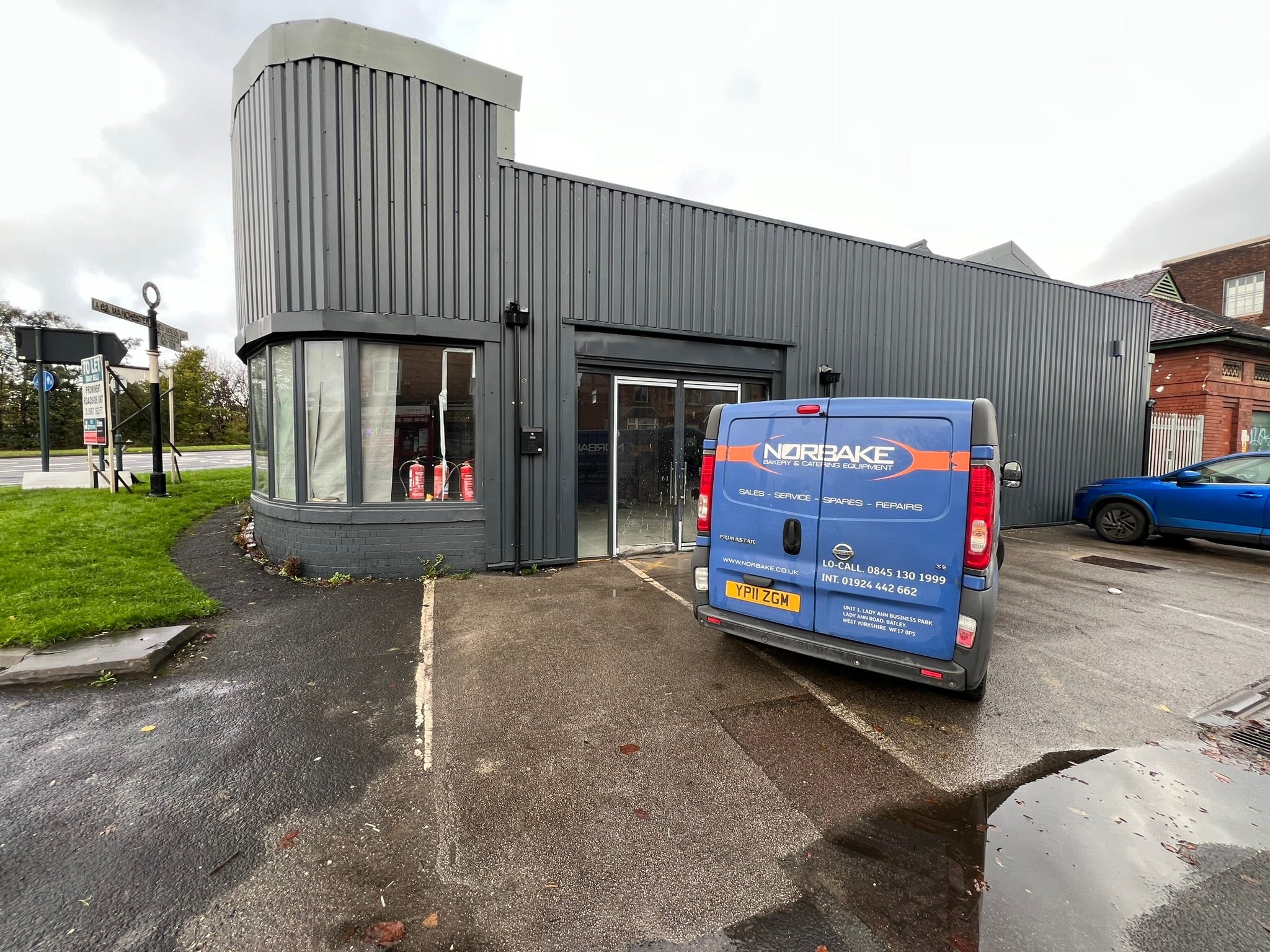 Empty grey-clad roadside commercial unit before the installation of YOH Burger restaurant signage.