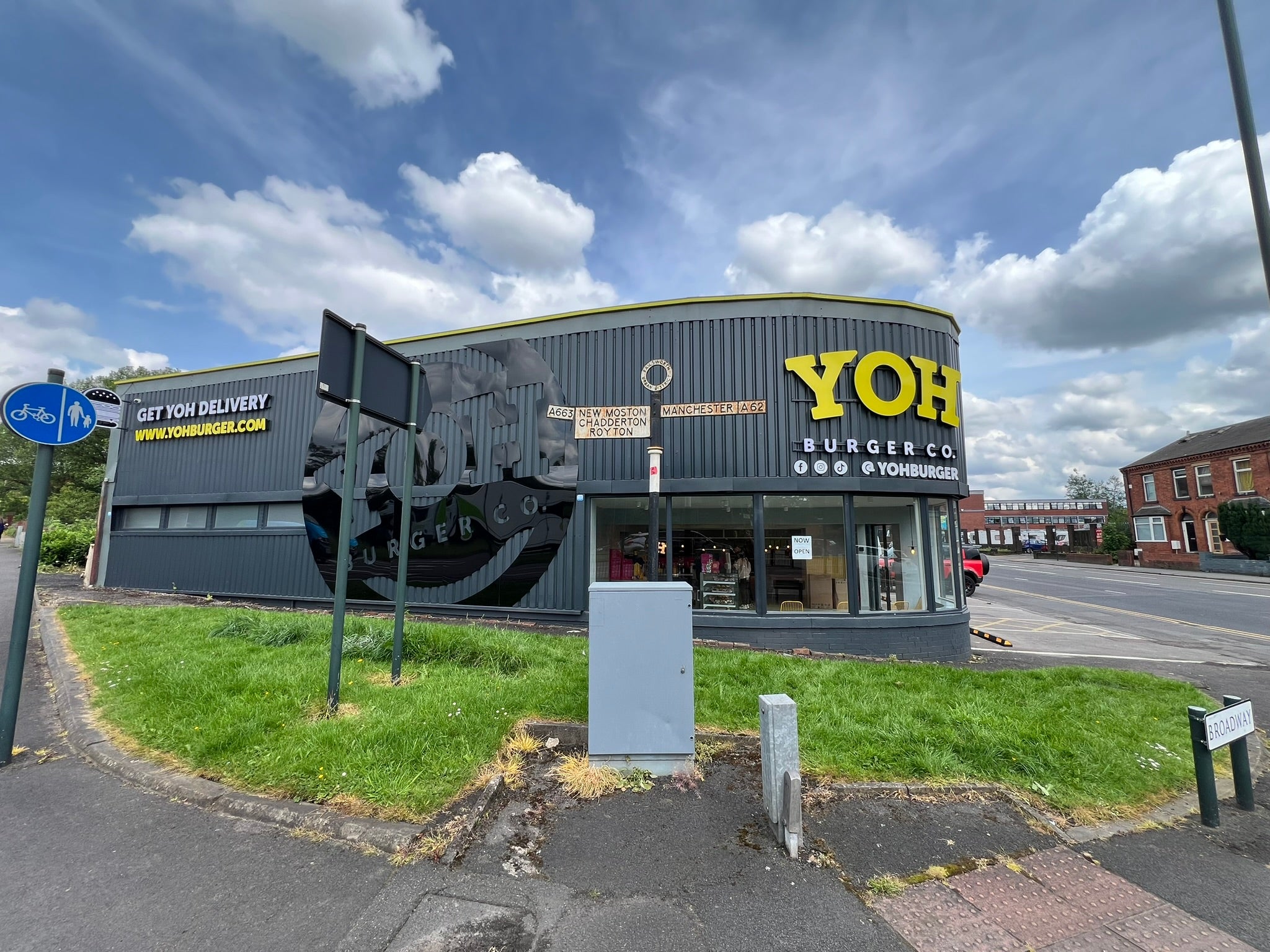 Side of the YOH Burger restaurant with a large gloss black logo and raised delivery signage.