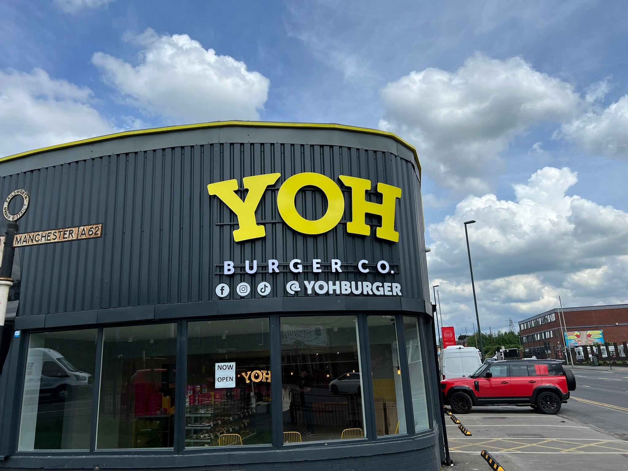 YOH Burger restaurant frontage with oversized yellow lettering, social media details and contrasting roofline trim.