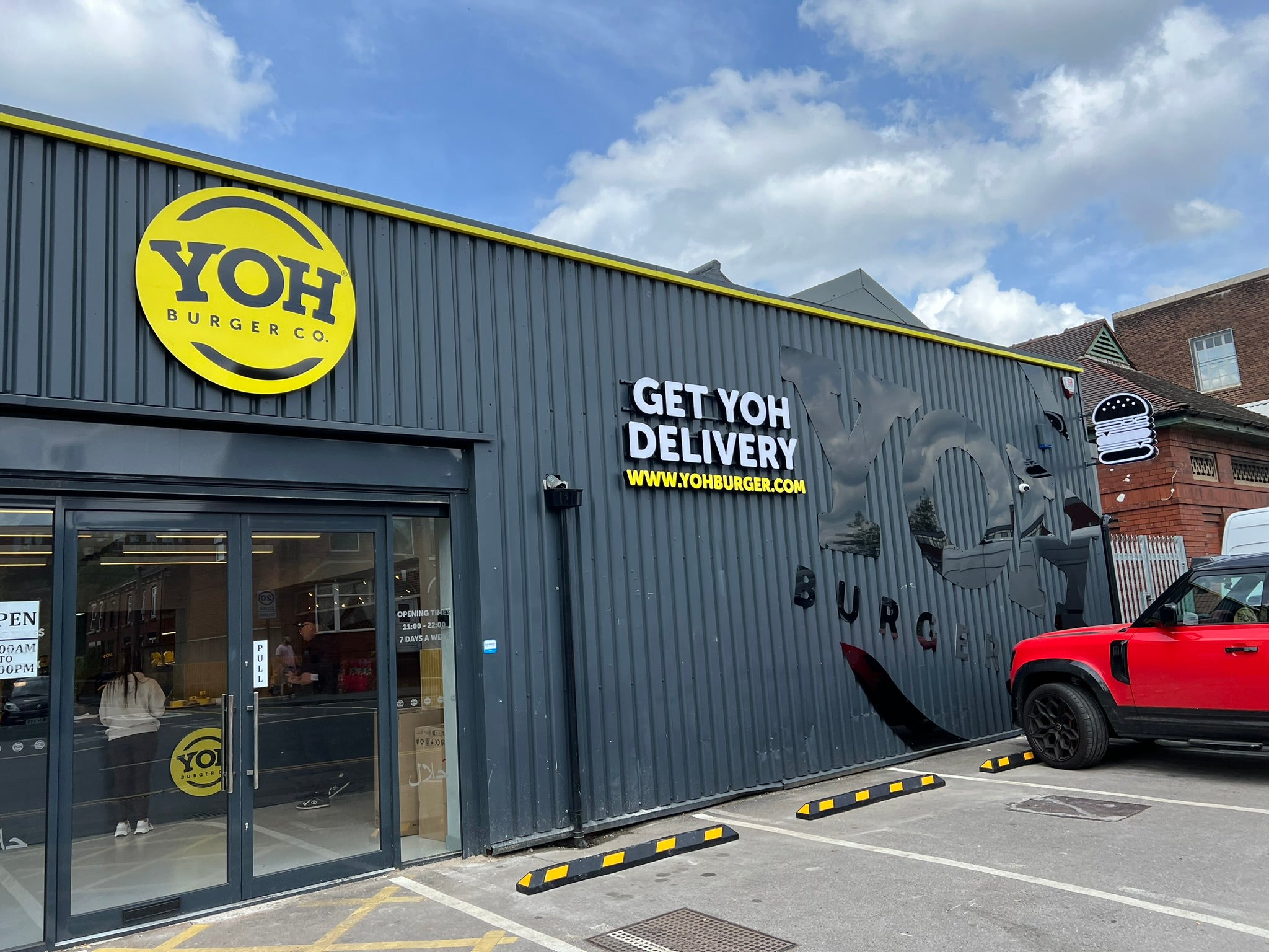 Completed YOH Burger restaurant exterior with large yellow branding, raised lettering and illuminated signage.
